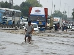 Vehicles and commuters are struggling to navigate through knee-deep water on NH-48 near Narsinghpur Village in Gurugram.(Parveen Kumar/HT Photo)